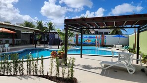 A swimming pool area with lounge chairs and a covered seating area. - Hotel Enseada dos Corais (Cabo de Santo Agostinho)