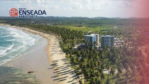 A coastal hotel with a beachfront view, palm trees, and modern buildings. - Hotel Enseada dos Corais (Cabo de Santo Agostinho)