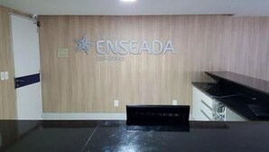 A hotel reception area with a wooden wall and a sign that reads "HOTEL ENSEADA." - Hotel Enseada dos Corais (Cabo de Santo Agostinho)