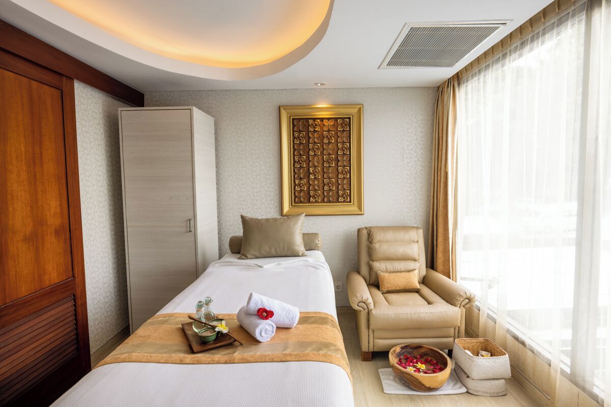 Habitación de hotel con cama, una silla, armario, un adorno de pared y ventana con cortinas.