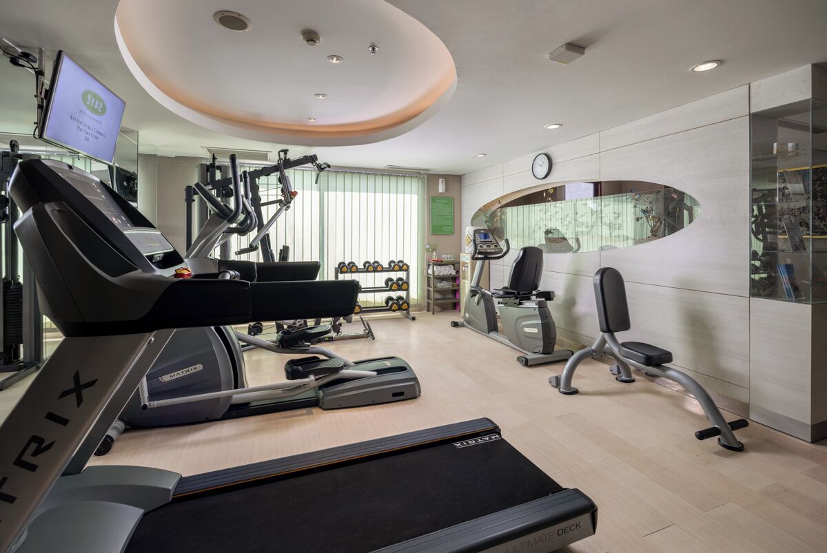 A modern gym with treadmills, elliptical machines, and weightlifting equipment.