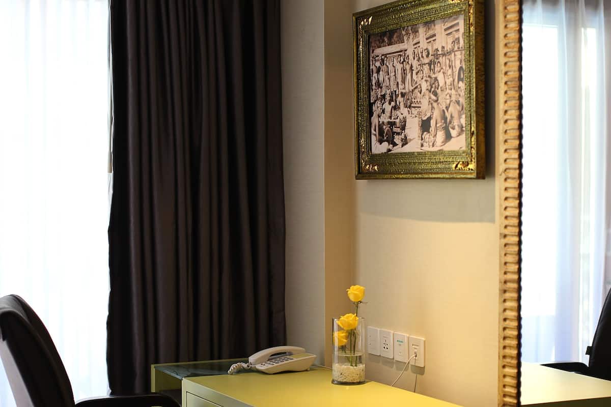 A hotel room with a desk, chair, and a large mirror.