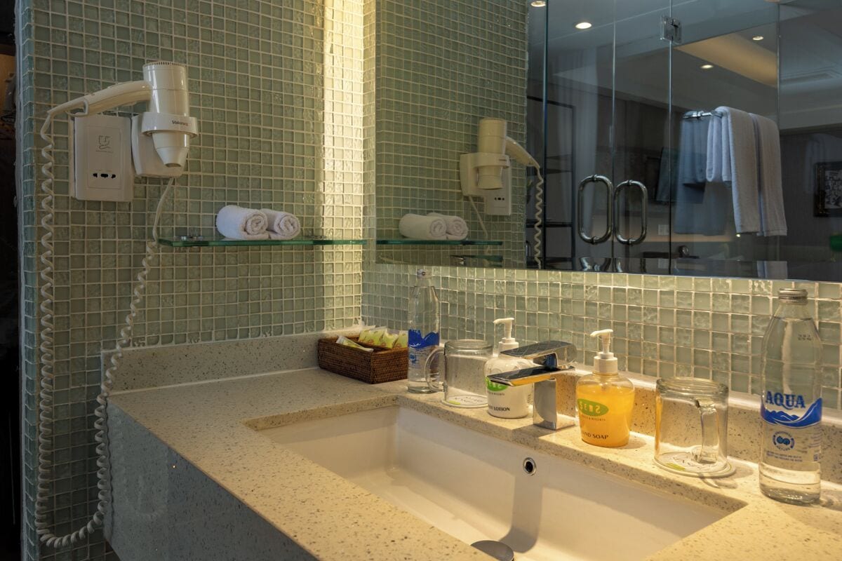 A bathroom with a glass shower enclosure, a sink with toiletries, and a towel rack.