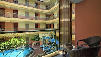 A multi-story hotel with balconies, a swimming pool, and outdoor seating.