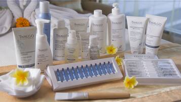 A variety of Thalgo skincare products arranged on a table with a white cloth, accompanied by a makeup brush and a tray of makeup items.