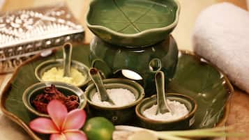 A tray with various spa products including a green bowl, a pink flower, and a white powder.