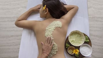 Una persona recibiendo un tratamiento para la espalda con una toalla blanca y una bandeja con pasta verde y otros artículos.