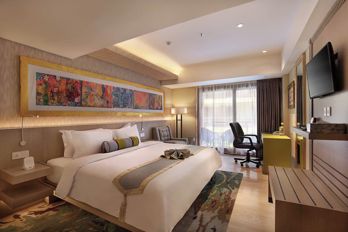 A modern hotel room with a large bed, a desk, a chair, a TV, and a large window with curtains.