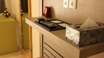 A hotel reception desk with a remote control, a tissue box, and a red clock on the wall.