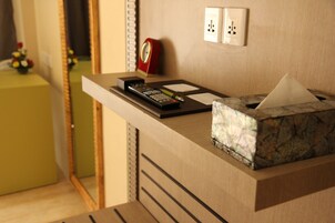 A hotel reception desk with a remote control, a tissue box, and a red clock on the wall.