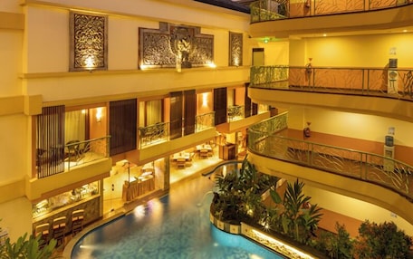 Un hotel de varios niveles con piscina central, balcones y plantas de interior.