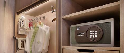 A compact, well-organized closet with wooden cabinetry, a hanging robe, and a built-in iron box.