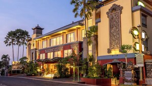 A hotel with a traditional architectural style, featuring a prominent entrance, palm trees, and a well-lit facade. - SenS Hotel and Spa Conference Ubud Town Centre (Ubud)