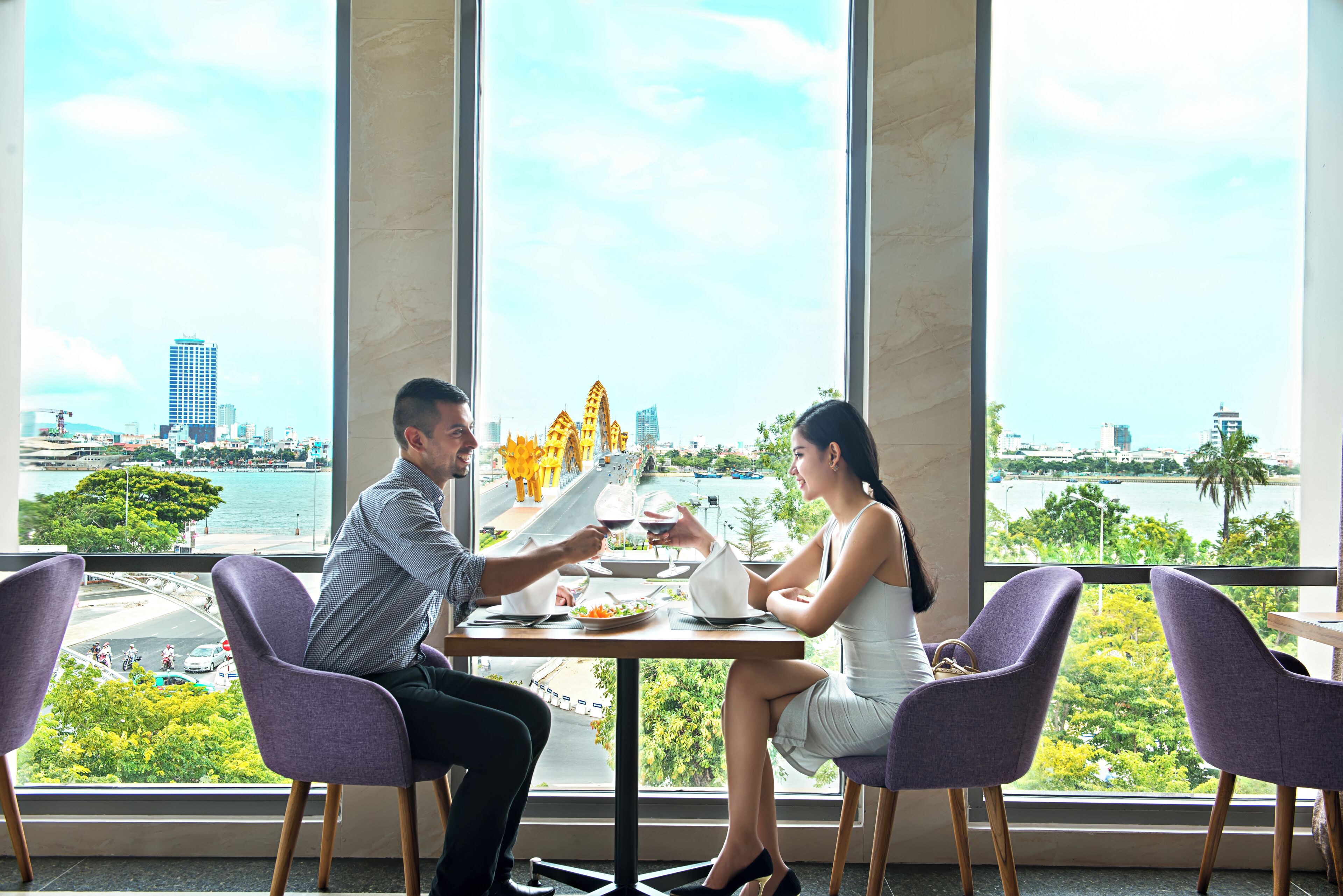 A dining area with a city view, large windows, and purple chairs.