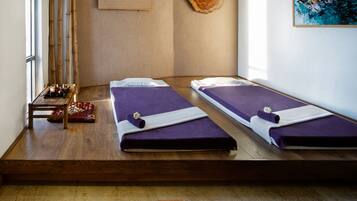 A modern room with two beds, a small table with a teapot, and a large abstract painting.