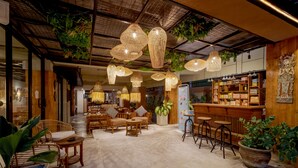 A spacious indoor area with wooden furniture, hanging wicker lamps, and a bar area with shelves of items.