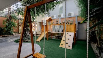 An indoor playground with a swing set, slides, and climbing structures.