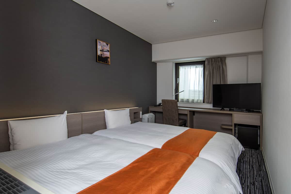 Een hotelkamer met een groot bed, een bureau, een stoel en een televisie.