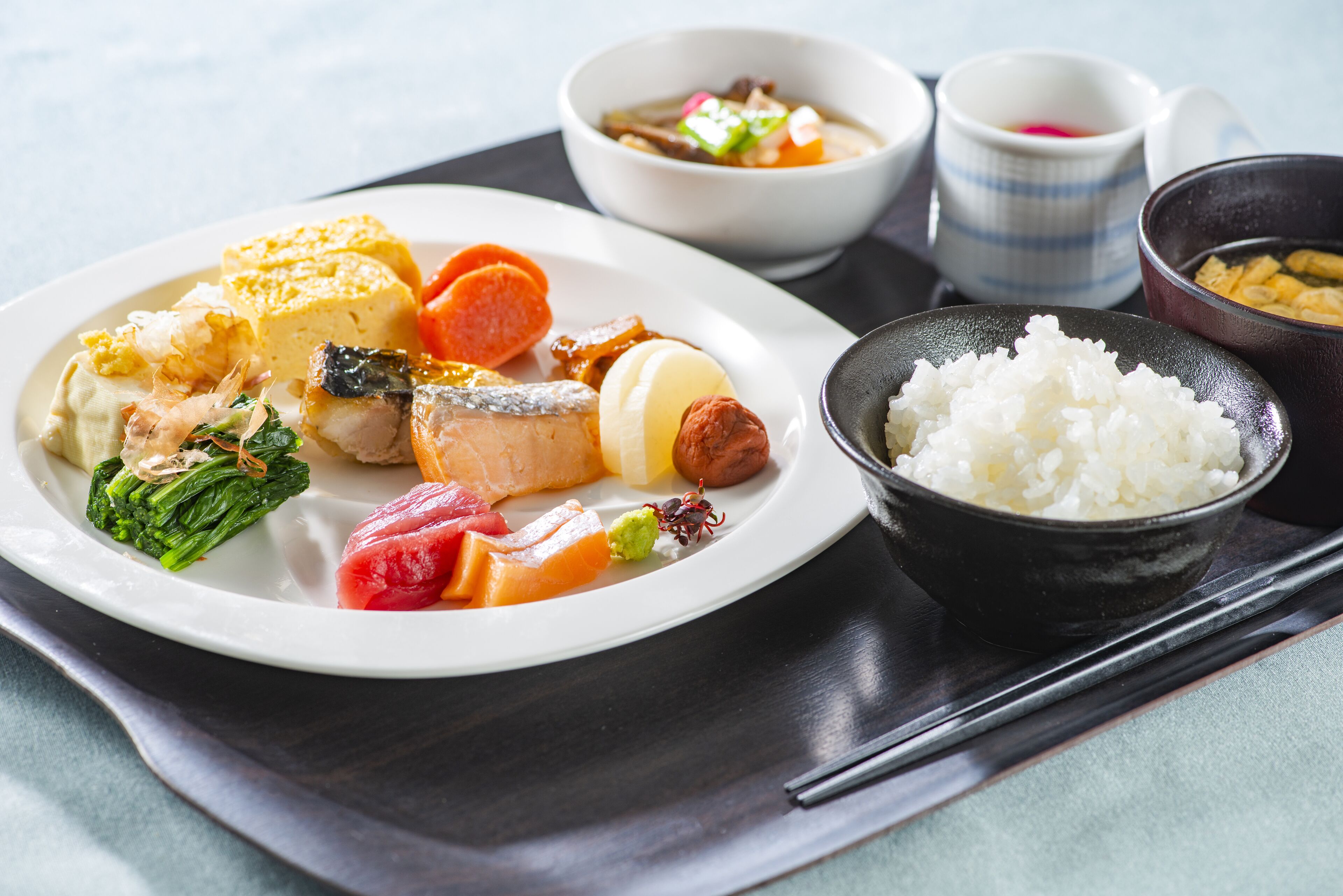 A traditional Japanese meal with rice, fish, and vegetables on a tray.