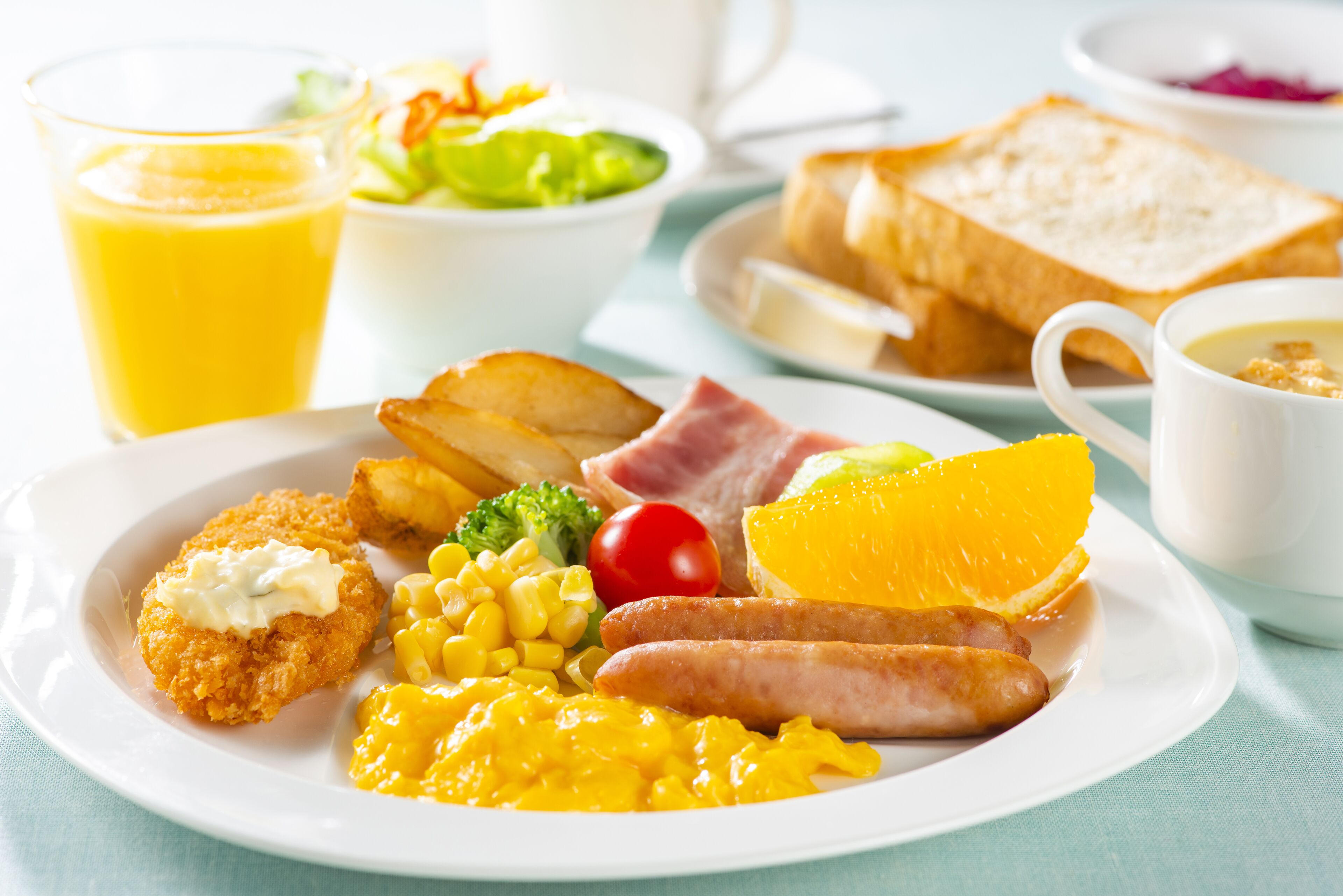 A breakfast plate with eggs, sausages, corn, and toast.