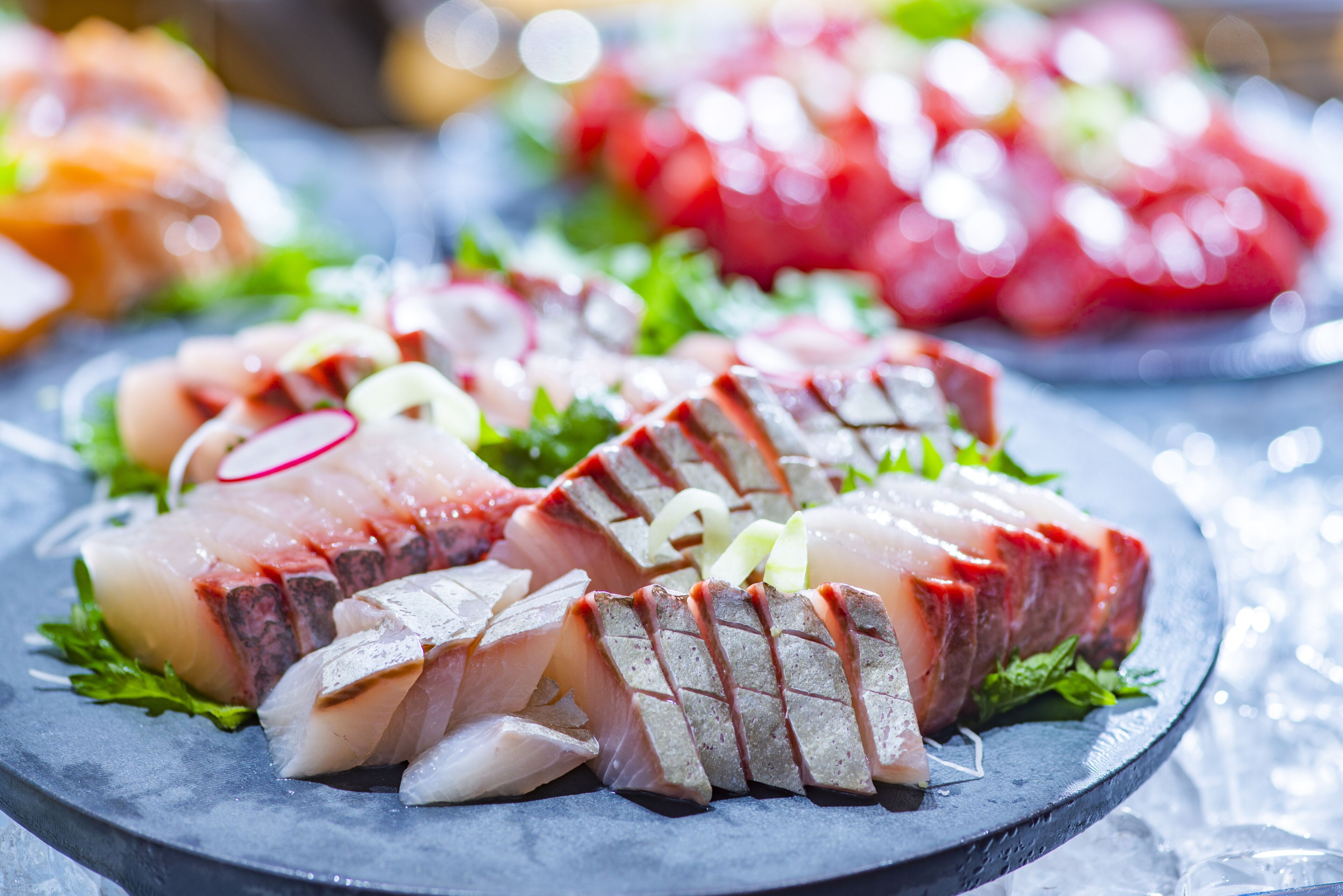 A platter of sliced fish and vegetables on a slate plate.