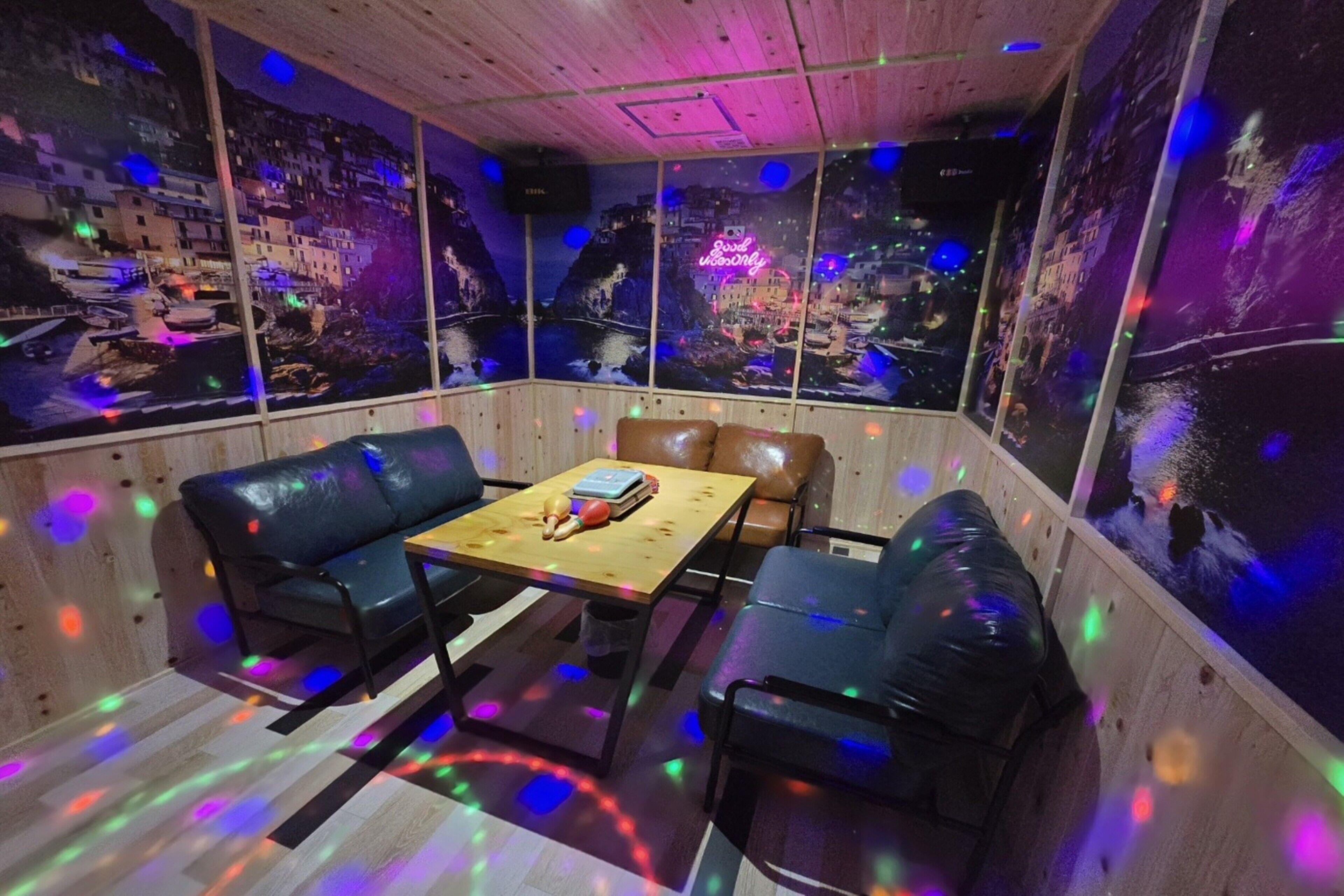 A room with a wooden ceiling, a wooden table, two leather sofas, and a cityscape mural on the walls.