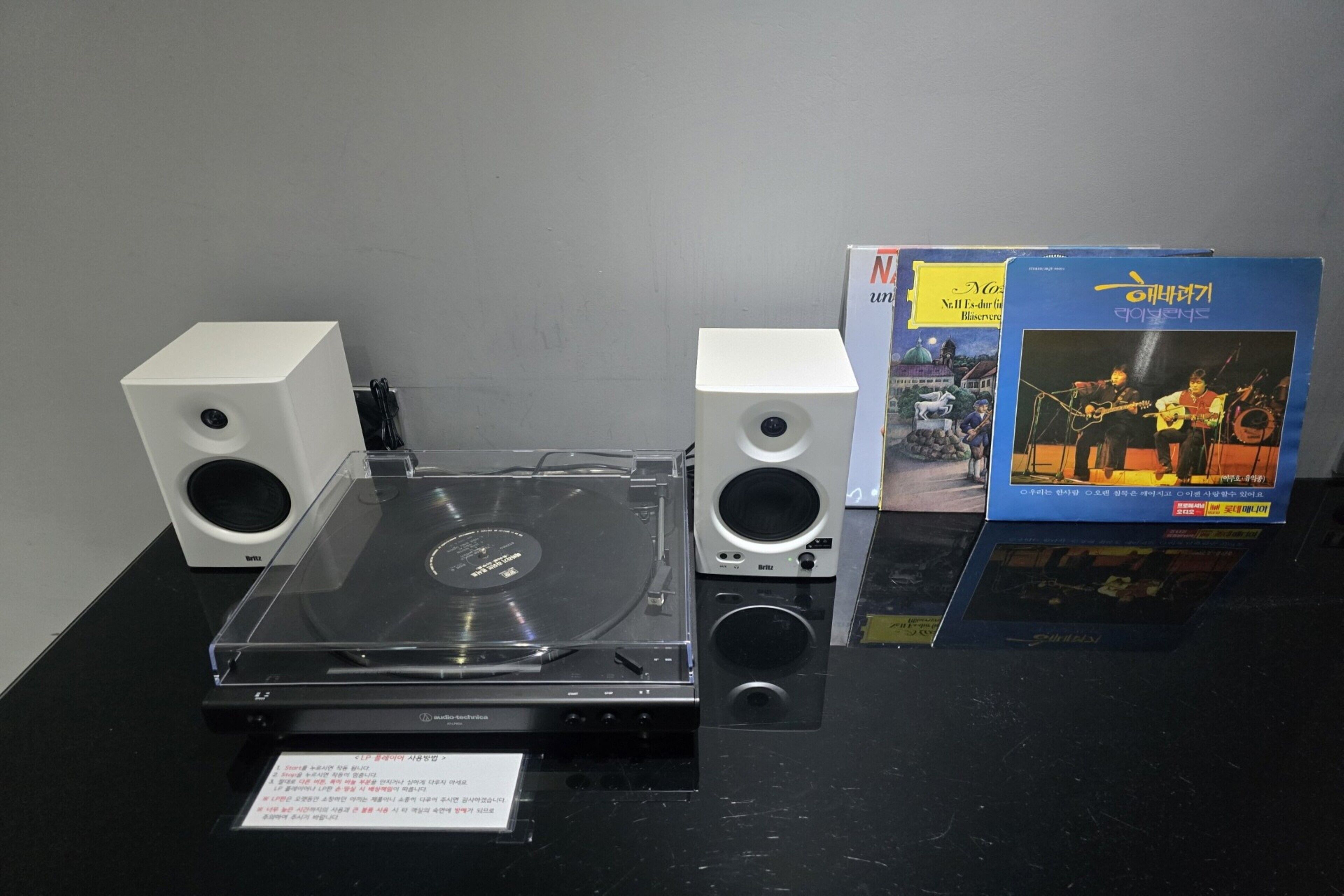 A turntable with speakers and a music album on a black table.