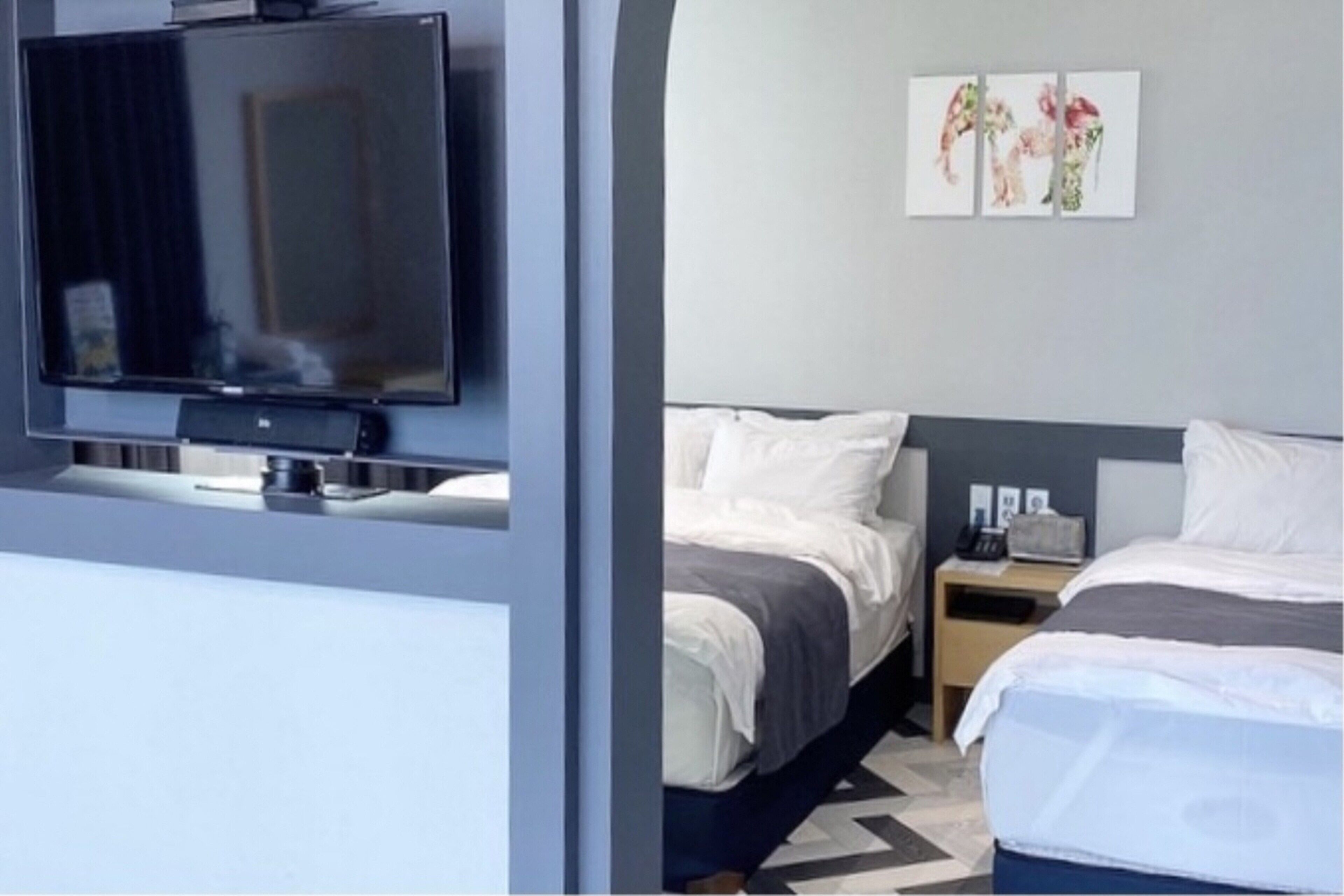 A hotel room with a bed, bedside table, and a television mounted on the wall.