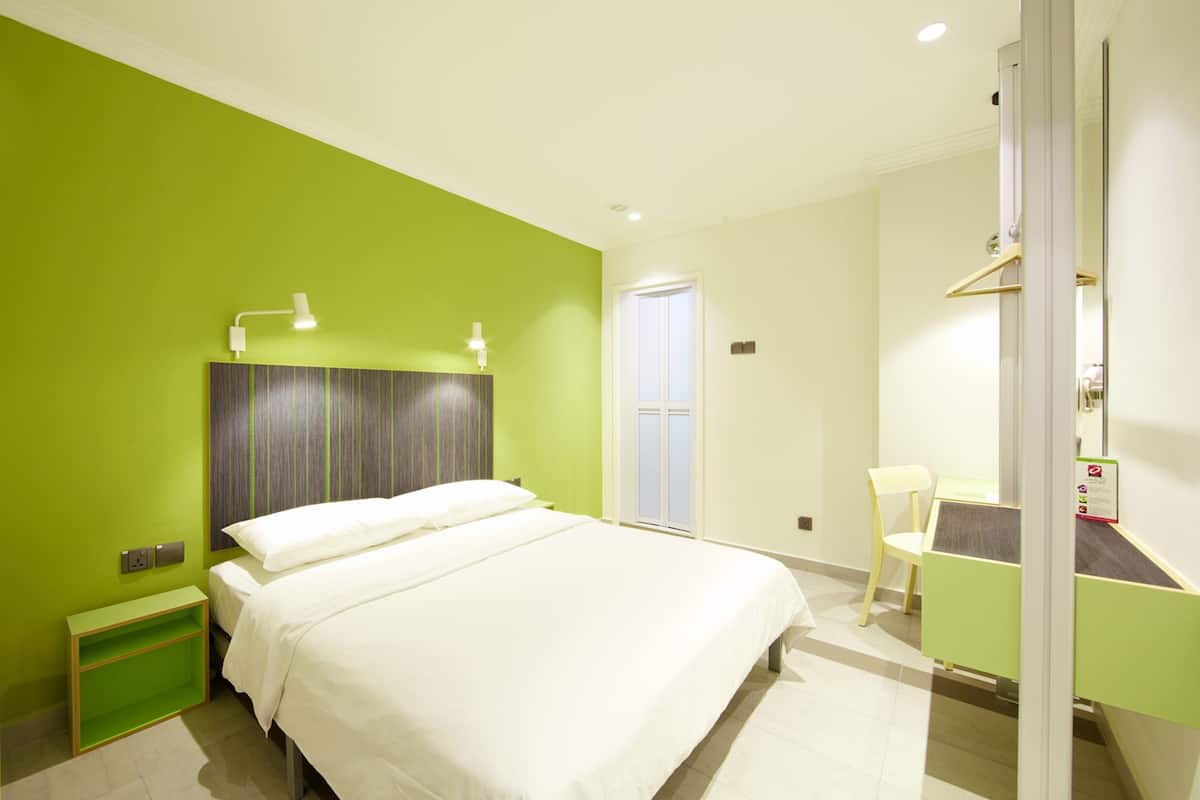 Une chambre d’hôtel comprenant un lit, une table de chevet, une chaise, un bureau et une armoire.