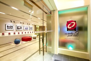 A modern interior with a glass door entrance, a wall with framed pictures, and a large poster with text.