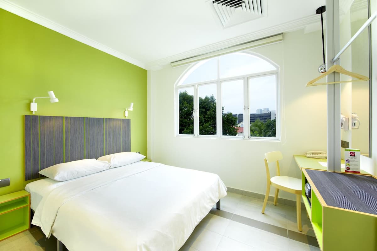 Une chambre d’hôtel moderne dotée d’un grand lit, d’un bureau avec une chaise, d’une grande fenêtre et d’une vue sur la ville.