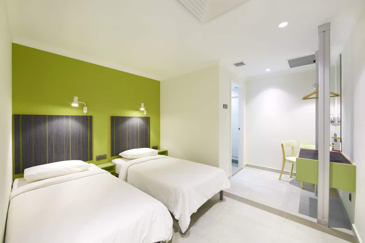 Une chambre d’hôtel avec deux lits, un bureau et une chaise.