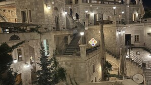 A stone building with multiple balconies and staircases, illuminated by street lamps. - Exedra Cappadocia (Ürgüp)