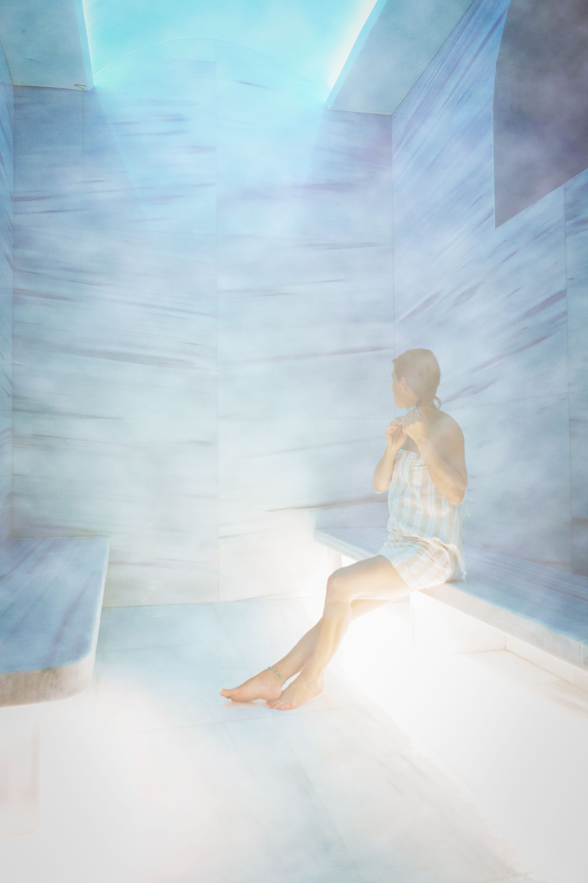 A person sitting in a room with a sloped ceiling and a bench.