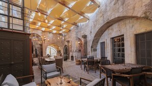An indoor courtyard with stone walls, wooden furniture, and hanging lights. - Exedra Cappadocia (Ürgüp)