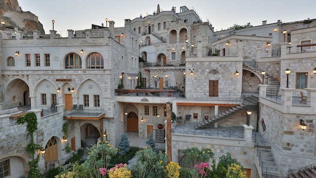 A historic stone building with multiple balconies, arched doorways, and a central courtyard with flowers. - Exedra Cappadocia (Ürgüp)