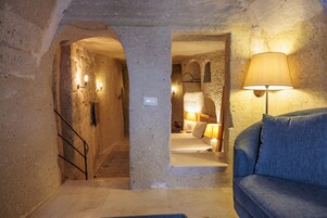 Una habitación acogedora con pared de piedra, una cama, un sofá azul y una lámpara.