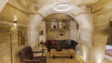 Un interior acogedor con un sillón de cuero, un sofá y una mesa de centro, todo frente a una pared de piedra texturizada.