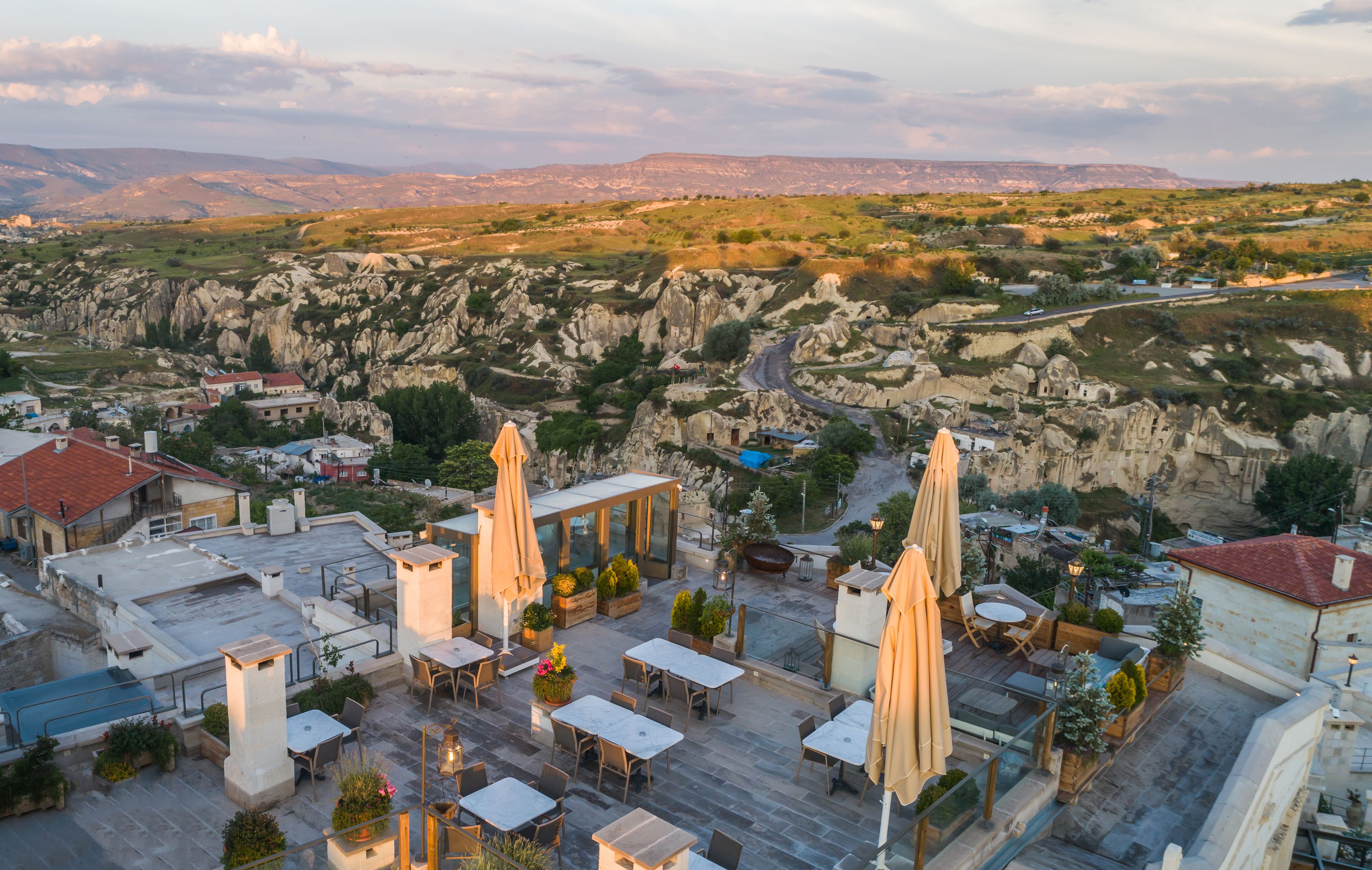 A rooftop terrace with outdoor seating, a pool, and views of rocky hills.
