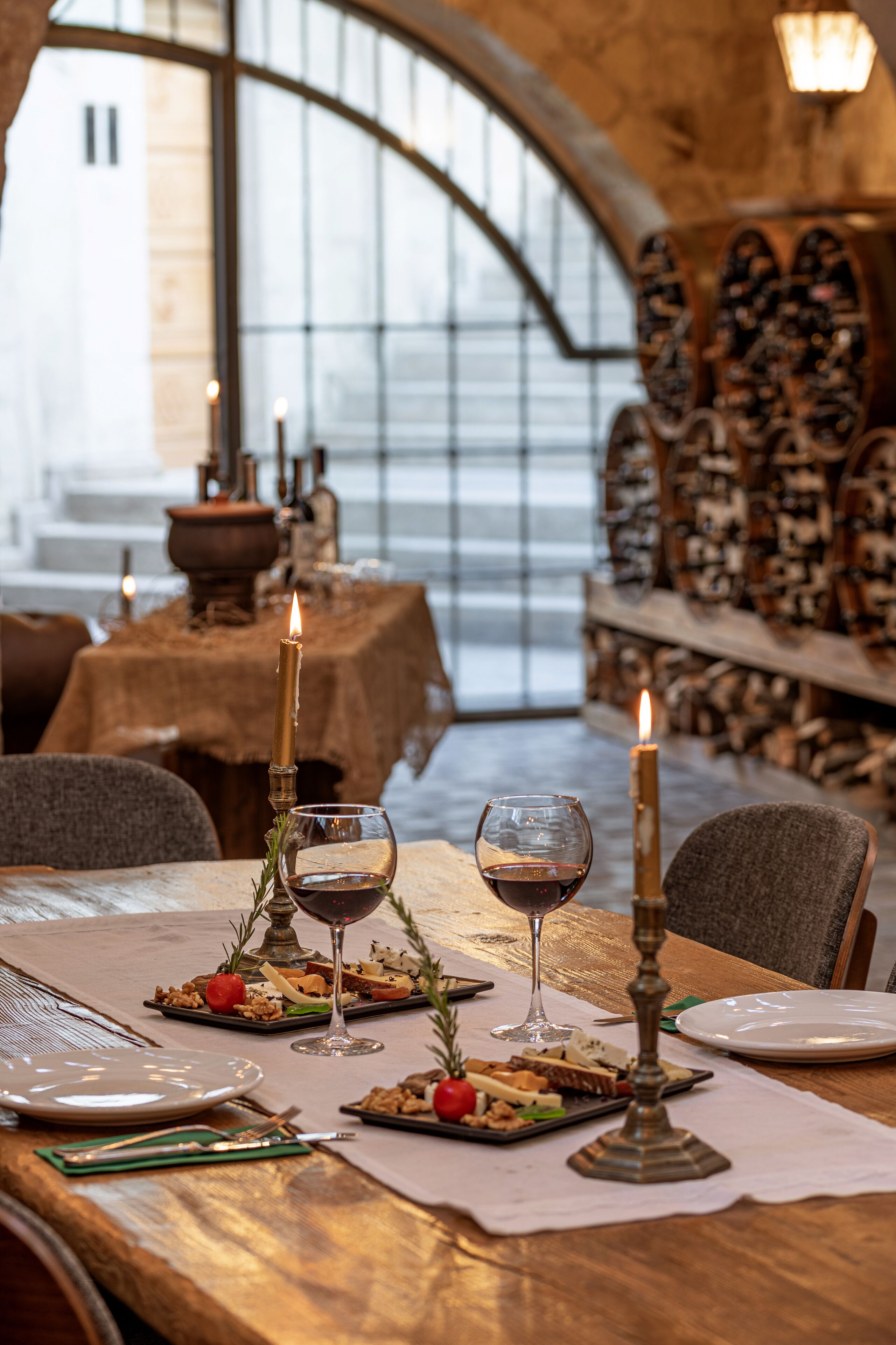 A dining table set with candles, wine glasses, and plates of food.