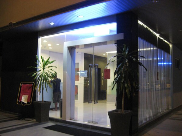 A hotel entrance with glass doors, potted plants, and a visible elevator.