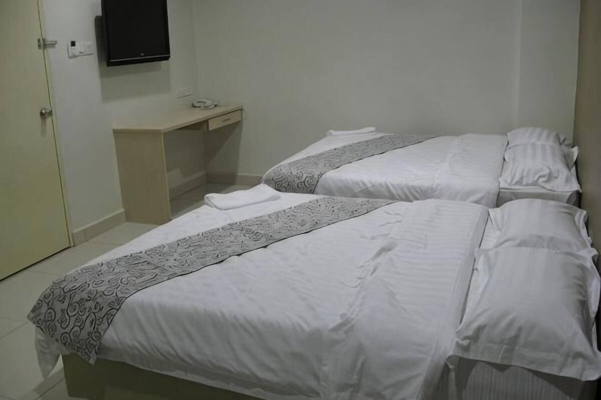 Ein Hotelzimmer mit zwei Betten, einem Schreibtisch, einem Fernseher und einer Tür.