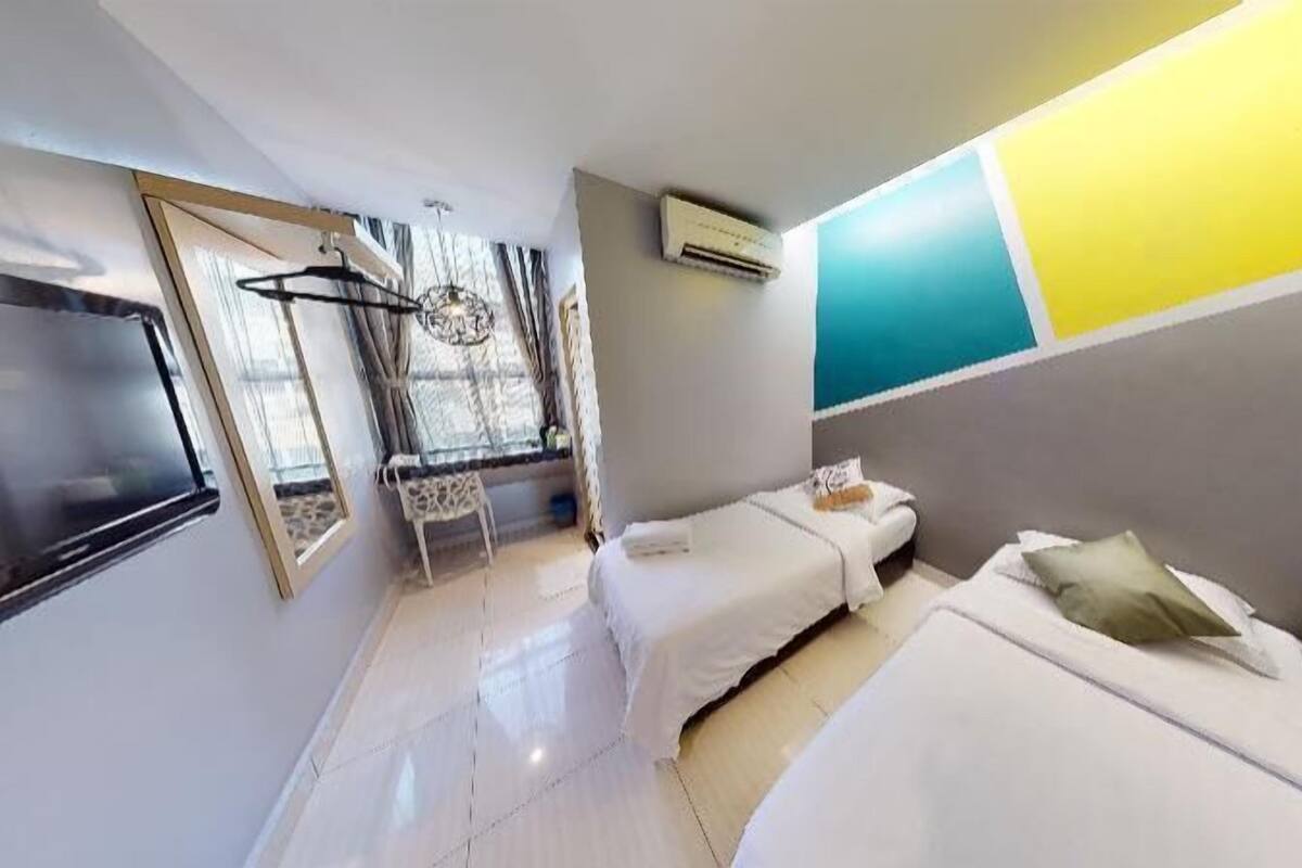 Ein modernes Hotelzimmer mit einem Bett, einem Sessel, einem Fernseher und einem Fenster mit Vorhängen.