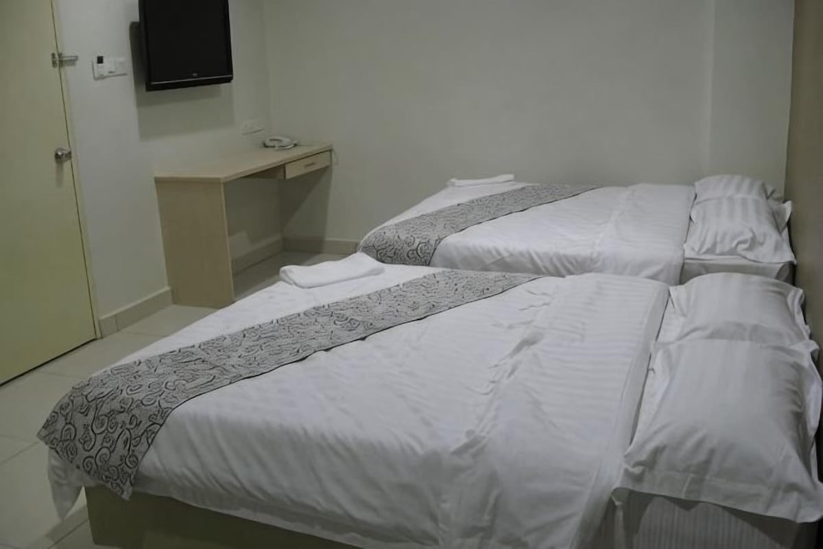 Ein Hotelzimmer mit zwei Betten, einem Schreibtisch, einem Fernseher und einer Tür.