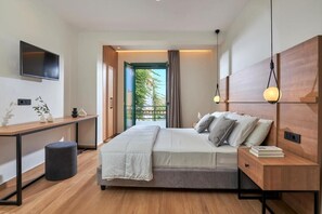 Une chambre moderne comprenant un lit, des tables de chevet, un bureau, un téléviseur et une vue sur l’extérieur.