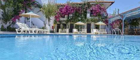 Una piscina al aire libre, sillones reclinables de piscina