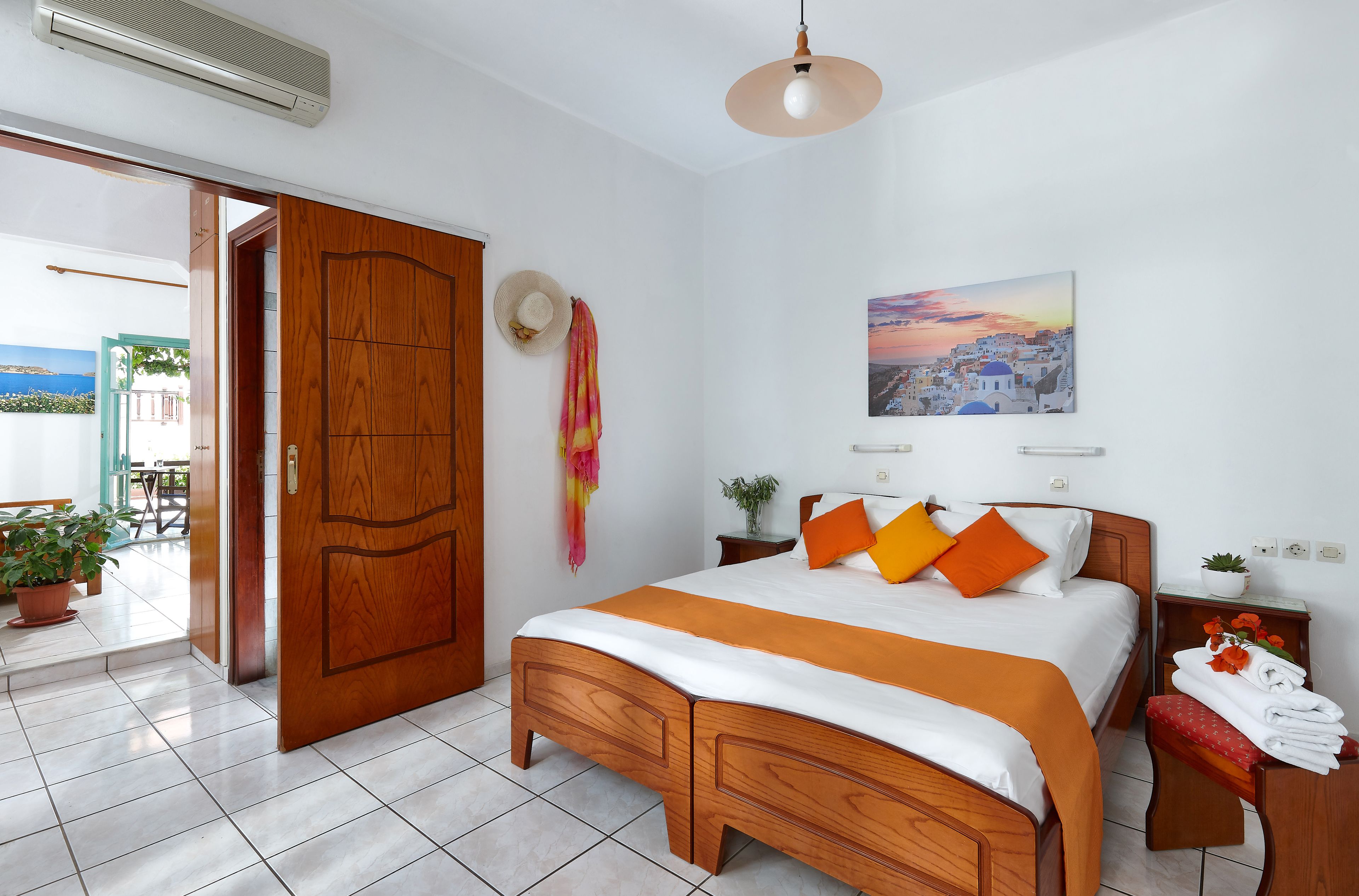 A hotel room with a wooden bed, a view of the outside, a painting of a cityscape, and a door leading to a balcony.
