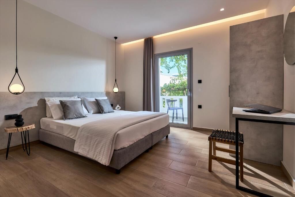 Een moderne slaapkamer met een bed, nachtkastjes, een bureau en uitzicht op de omgeving.