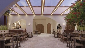 Um restaurante com chão de pedra, mesas e cadeiras de madeira e teto de vidro.
