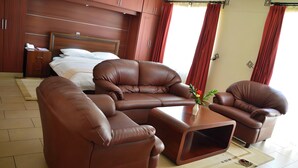 A modern hotel room with a large bed, a sofa set, and a coffee table.